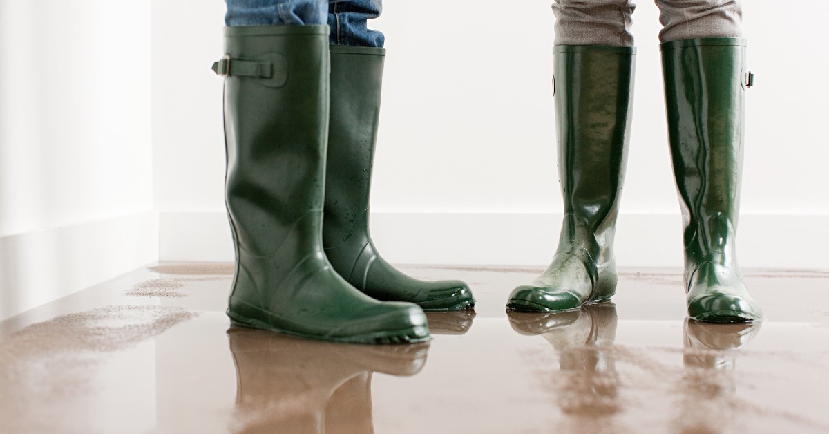Two people wearing rain boots in a flooded house